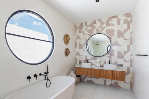 Localita House في كيروبوكان: حمام مع حوض ومرآة مستديرة