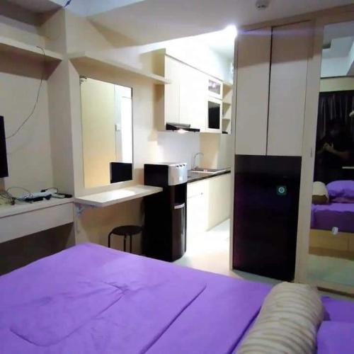 ein Schlafzimmer mit einem lila Bett und eine Küche mit einem Schreibtisch in der Unterkunft Andalemi Home Stay in Ciwidey