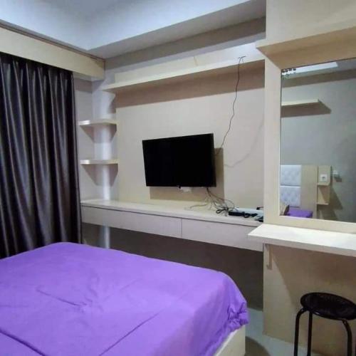 um quarto com uma cama e uma secretária com uma televisão em Andalemi Home Stay em Ciwidey