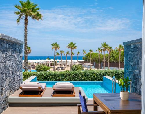 ヘルソニソスにあるNana Princess Suites Villas & Spaのスイミングプールのそばにパティオ(テーブル、椅子付)