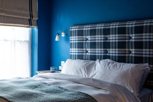1 dormitorio con paredes azules y 1 cama con almohadas blancas en The George at Backwell en Nailsea