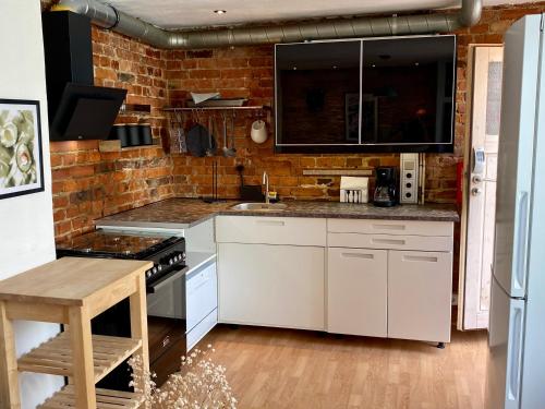 a kitchen with white cabinets and a brick wall at Haus No. 16 in Ratzeburg