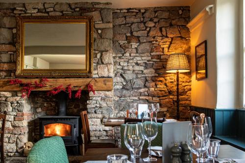 a dining room with a stone wall and a fireplace at The George at Backwell in Nailsea