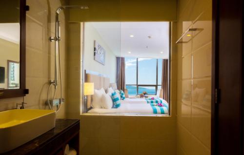 ein Bad mit einem Waschbecken und ein Bett mit einem Fenster in der Unterkunft Avatar Danang Hotel in Đà Nẵng