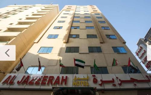 a tall building with a sign in front of it at Al Jazeerah Hotel in Sharjah