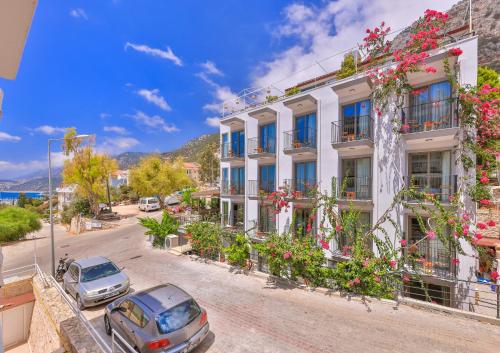 a building with flowers and cars parked in front of it at Aphrodite Hotel Kaş in Kaş