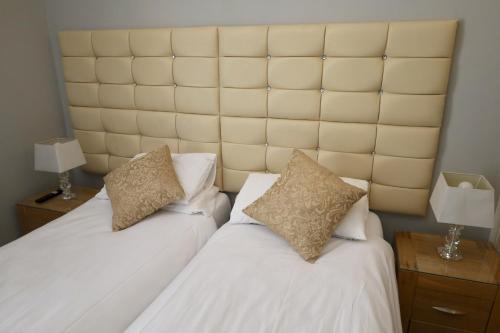 a bedroom with two beds with white sheets and pillows at Brighton Inn Boutique Guest Accommodation in Brighton & Hove