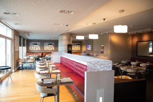 a restaurant with a red bench and tables and chairs at Premier Inn Doha Education City in Doha
