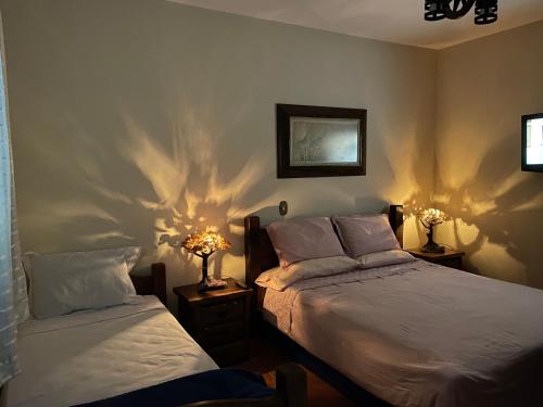 two beds in a bedroom with their shadows on the wall at Sitio Renovo Juquitiba Hospedagens in Juquitiba