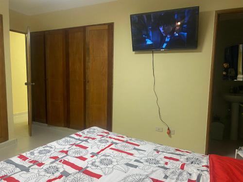 a bedroom with a bed and a tv on the wall at Casa Apartamento Valentina in Santo Domingo