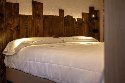 a large white bed with a wooden head board at Eco Dimora Baltea - Affittacamere al Verde villaggio di Rumiod in Saint-Pierre