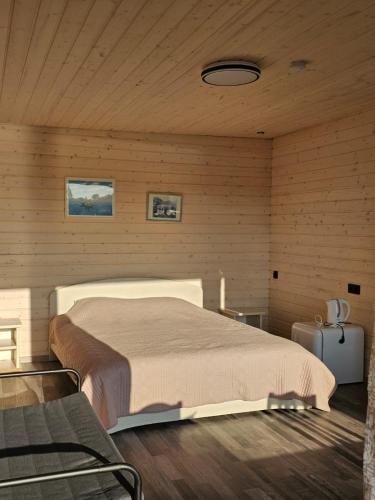 a bedroom with a large bed in a wooden wall at Tūjas dīķi in Tūja