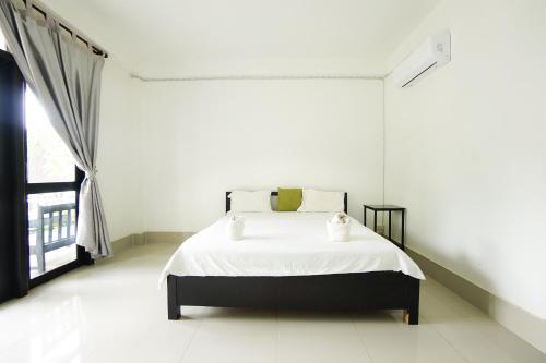 a white bedroom with a bed and a window at Mr Tho's Bungalows in Don Det