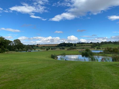 a view of a golf course with a pond on a green at The Black Swan Shepherd Hut in Ketton