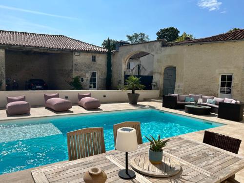 a swimming pool with some chairs and a table at La part des Anges in Fontenet