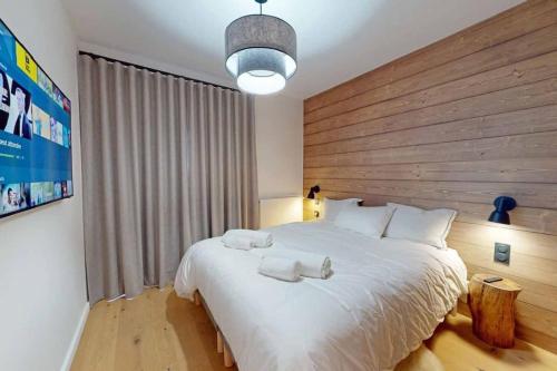 um quarto com uma grande cama branca e uma cabeceira em madeira em Appartement neuf à Mottaret / A12 em Les Allues