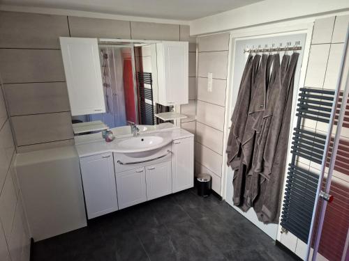 W białej łazience znajduje się umywalka i lustro. w obiekcie Föller´s Gästehaus w mieście Neu-Anspach