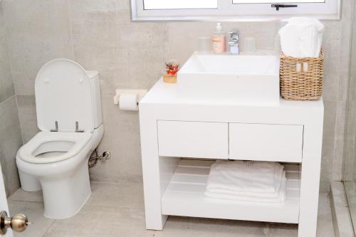 a white bathroom with a toilet and a sink at The Donga House - Luxury Home near Scottburgh Beach in Scottburgh