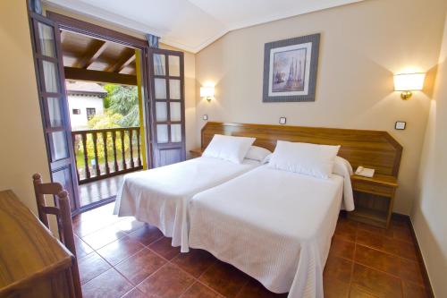 a bedroom with a large white bed and a window at Apartamentos Capriccio in Santillana del Mar