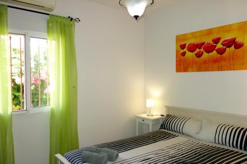 a bedroom with a bed and a painting of red flowers at Casa Limón - Ferienhaus - Pool - Klimaanlage - W-Lan in Chiclana de la Frontera