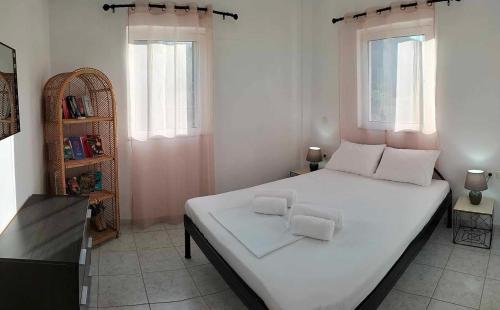 sypialnia z dużym białym łóżkiem i 2 oknami w obiekcie Villa Helen's Olive Garden w mieście Xerokampos
