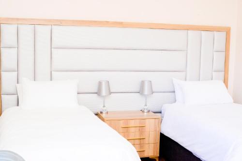 a bedroom with two beds and a wooden headboard at The Donga House - Luxury Home near Scottburgh Beach in Scottburgh