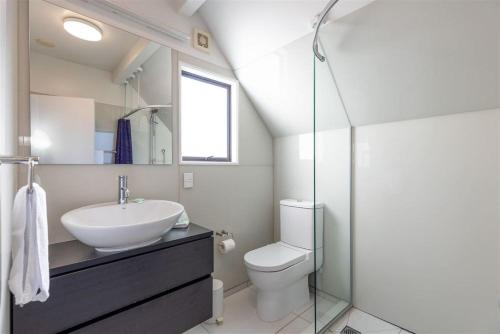 a white bathroom with a sink and a toilet at Wharfside Apartment in Akaroa