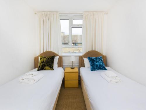 2 łóżka pojedyncze w pokoju z oknem w obiekcie Pass the Keys - Beautiful Flat with balcony in Swiss Cottage, London w Londynie