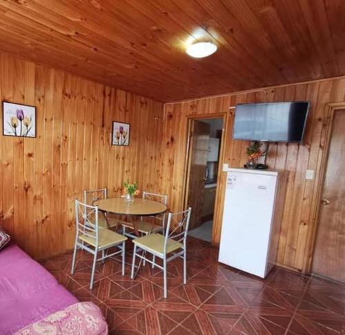 ein Esszimmer mit einem Tisch und einem Kühlschrank in der Unterkunft Cabañas amobladas en salto del laja a 2 minutos del puente salto del laja in El Manzano