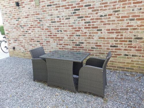 une table et deux chaises à côté d'un mur de briques dans l'établissement Studio Me Me, à Chastre-Villeroux-Blanmont