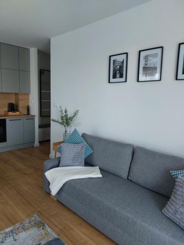 a living room with a gray couch and a kitchen at La Casa in Piotrków Trybunalski