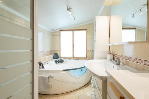 baño con bañera grande y lavamanos en Maison avec piscine et belle vue en Lédenon