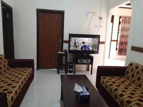 uma sala de estar com dois sofás e uma televisão em Mawar Bed and Breakfast em Bajawa