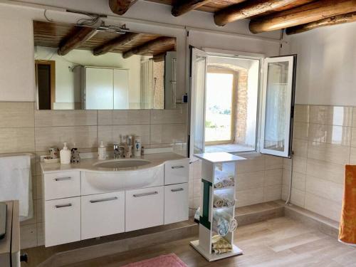een badkamer met een wastafel, een spiegel en een raam bij Casale Bellavita in San Giovanni Ilarione