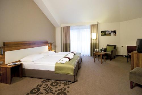a hotel room with a bed and a living room at Mercure Tagungs- & Landhotel Krefeld in Krefeld
