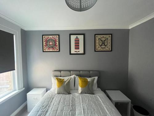 sypialnia z łóżkiem z czterema obrazami na ścianie w obiekcie The E17 Suite w Londynie