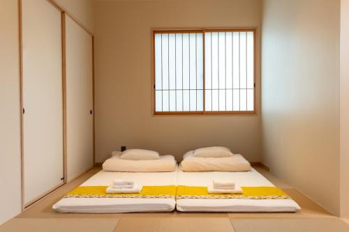two beds in a room with a window at Irodori Hotel UGUISU in Fukuoka