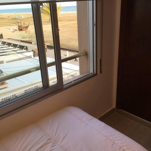 um quarto com uma janela com vista para a praia em Apartamento 1ª linea de mar em Comarruga