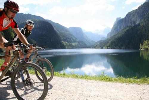 two people riding bikes next to a lake at Appartement Mühlkogel mit Indoorpool und Sauna in Bad Goisern
