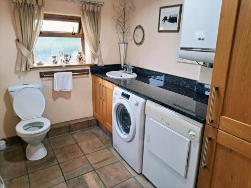 a bathroom with a washing machine and a sink at The Old Mill Barn with Hot Tub and Private Pool in Wirral
