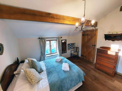 a bedroom with a bed and a dresser and a window at The Old Mill Barn with Hot Tub and Private Pool in Wirral