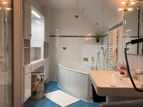 ein weißes Badezimmer mit einer Badewanne und einem Waschbecken in der Unterkunft Ferienwohnung Fördefreude in Wassersleben