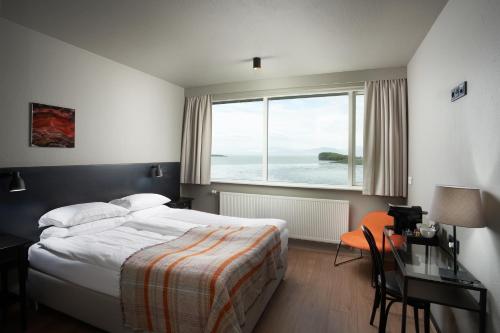 a bedroom with a bed and a desk and a large window at Höfn - Berjaya Iceland Hotels in Höfn