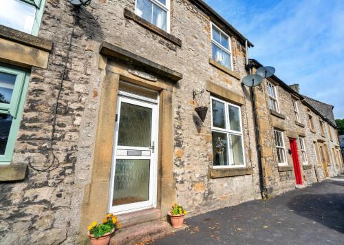 un antiguo edificio de piedra con macetas en una calle en Finest Retreats - Stonelea, en Tideswell