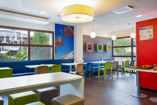 a dining room at a restaurant with tables and chairs at Ibis Budget Grenoble Sud Seyssins in Seyssins