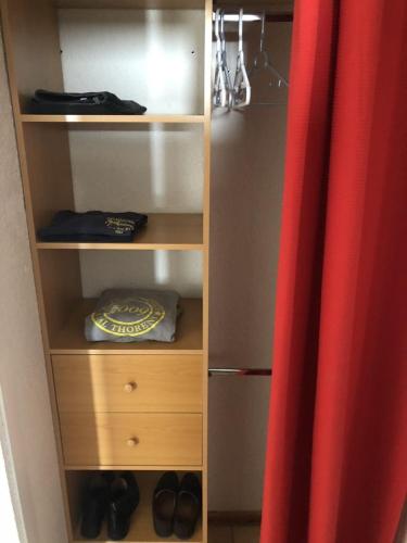 un placard avec un rideau rouge et quelques chaussures dans l'établissement Le Joker Vue Cime Caron Calm & Cosy, à Val Thorens