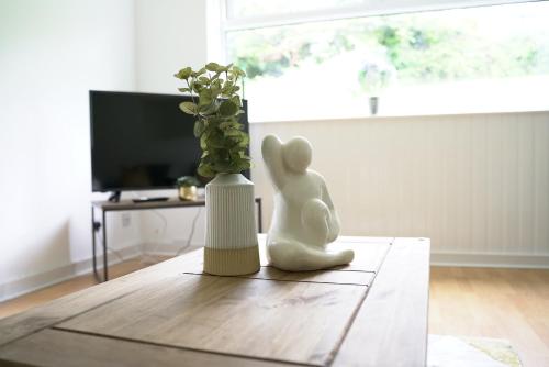 Una figurita blanca sentada en una mesa junto a un jarrón. en Queensferry Apartment en North Queensferry