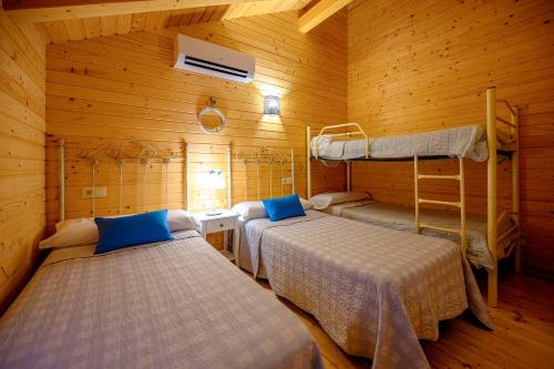 a room with two beds in a wooden cabin at Madera y Miel Casa Rural con niños en Puy du Fou in Guadamur