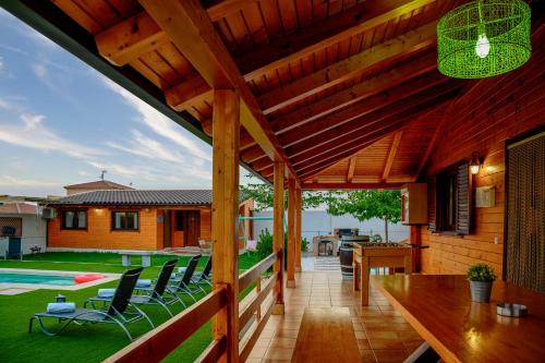 una terraza de madera con sillas, una mesa y una casa en Madera y Miel Casa Rural con niños en Puy du Fou, en Guadamur