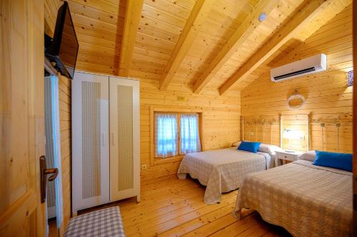 a bedroom with two beds in a wooden cabin at Madera y Miel Casa Rural con niños en Puy du Fou in Guadamur